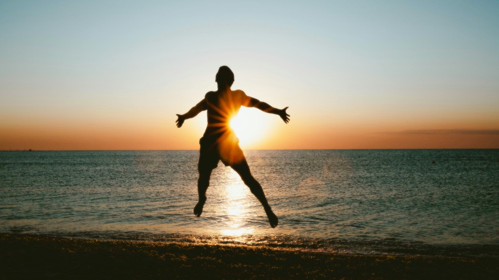 Person leaping joyfully at the beach during sunset